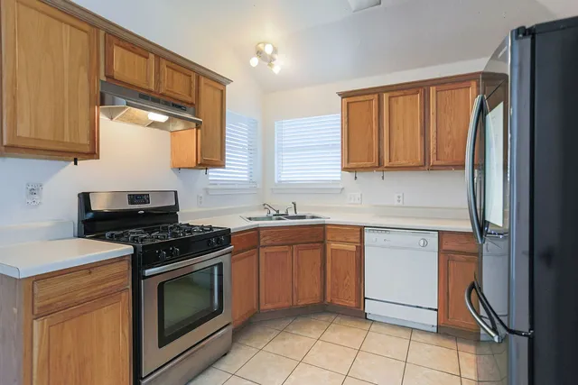 a kitchen with stainless steel appliances granite countertop a stove a sink and a refrigerator