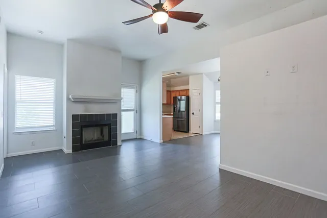 a view of an empty room with wooden floor fireplace and a window