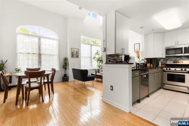 a kitchen with stainless steel appliances granite countertop a stove top oven a sink a dining table and chairs with wooden floor