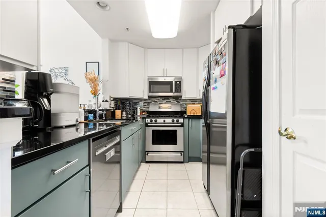 a kitchen with granite countertop a refrigerator and a stove top oven