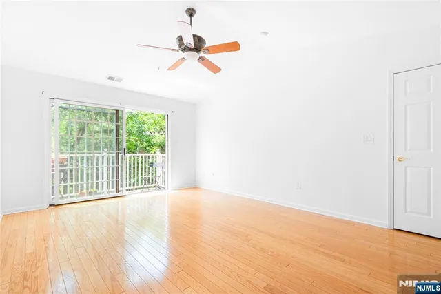 a view of empty room with wooden floor and fan