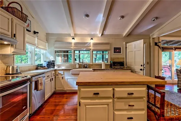 a large kitchen with stainless steel appliances a stove a sink dishwasher and cabinets with wooden floor