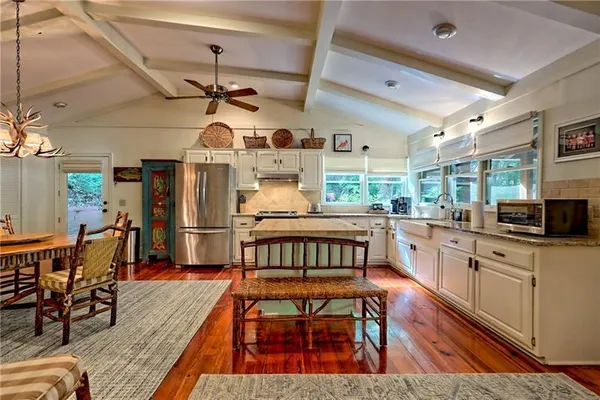 a kitchen with stainless steel appliances kitchen island granite countertop a table chairs in it and wooden floors