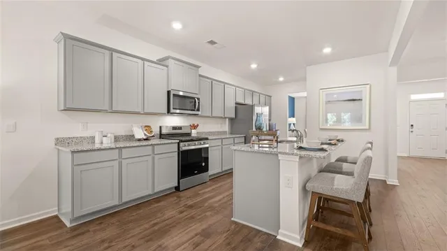 a living room with furniture a wooden floor and kitchen view