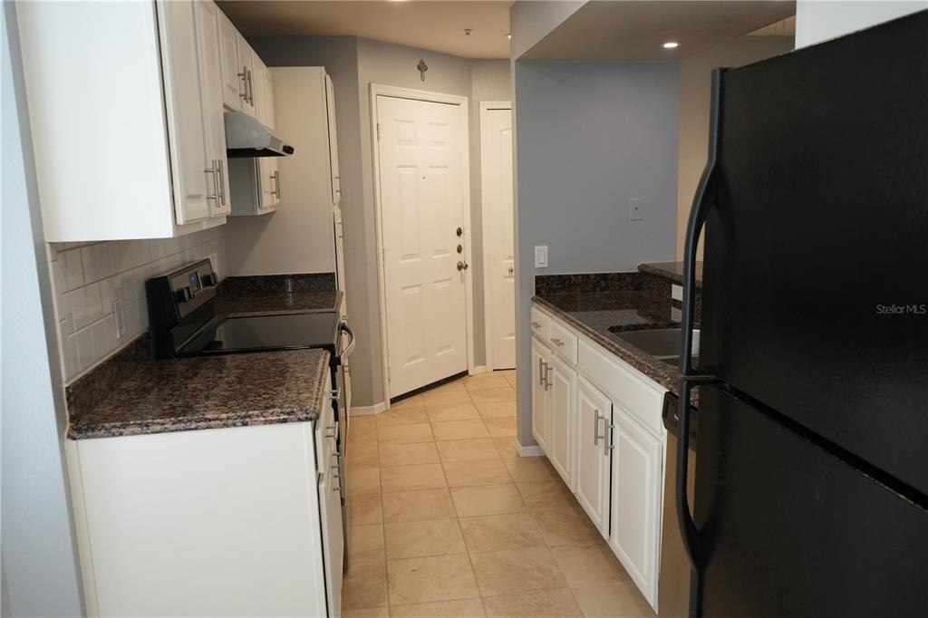 416 Summit Ridge Place, Unit 316 Longwood, FL 32779 - Photo 7 of 24 a kitchen with granite countertop a refrigerator and a sink