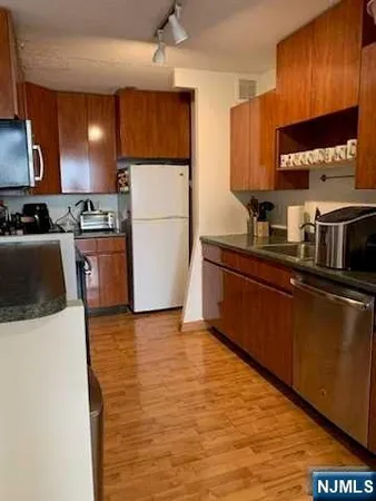 a kitchen with stainless steel appliances granite countertop a sink a stove a refrigerator a microwave oven with cabinets and wooden floor