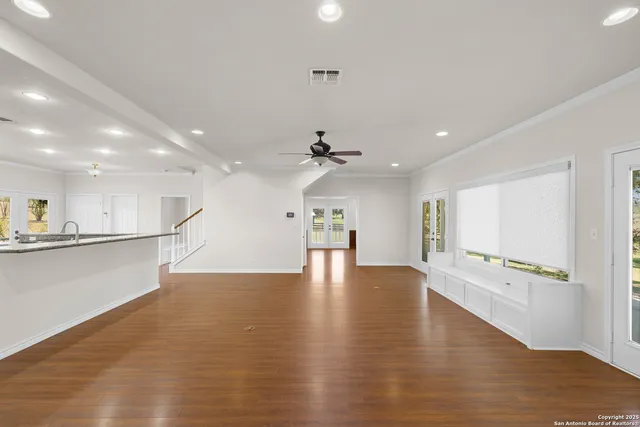 a view of an empty room with wooden floor and a ceiling fan
