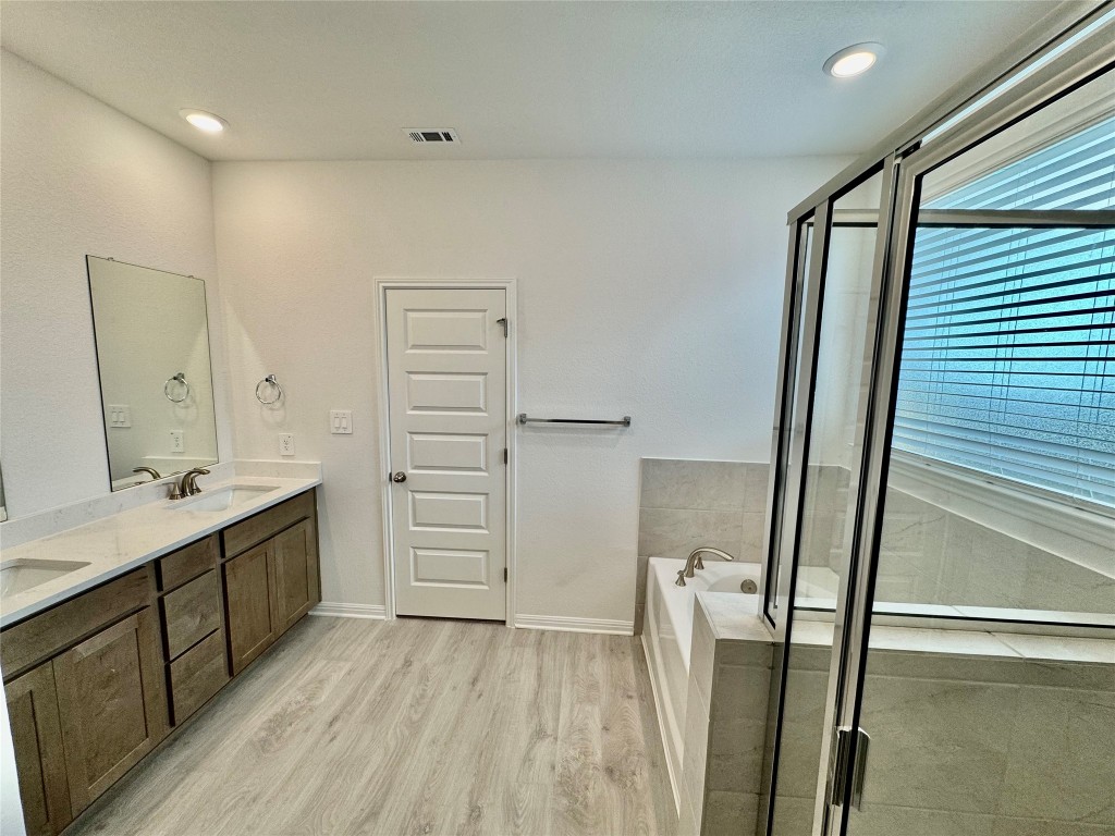 1788 South Main Street Kyle, TX 78640 - Photo 4 of 7 Full bath with double vanity, a bath, a shower stall, light wood-style flooring, and recessed lighting