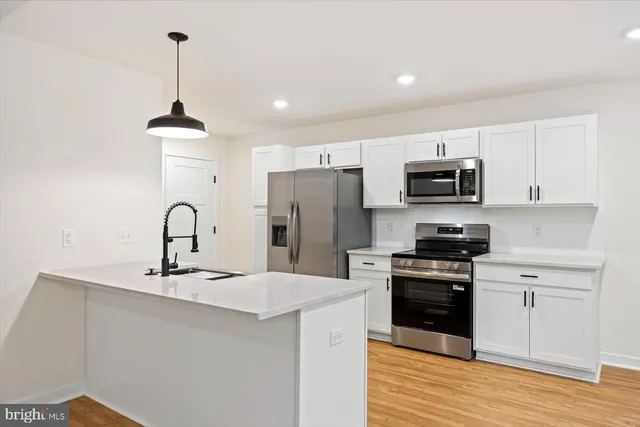 a kitchen with kitchen island granite countertop a sink stainless steel appliances and white cabinets