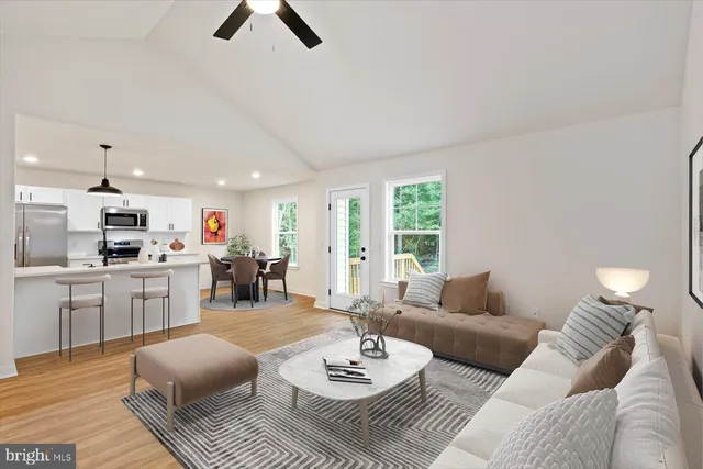a living room with furniture kitchen view and a large window