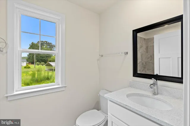 a bathroom with a toilet sink vanity and mirror