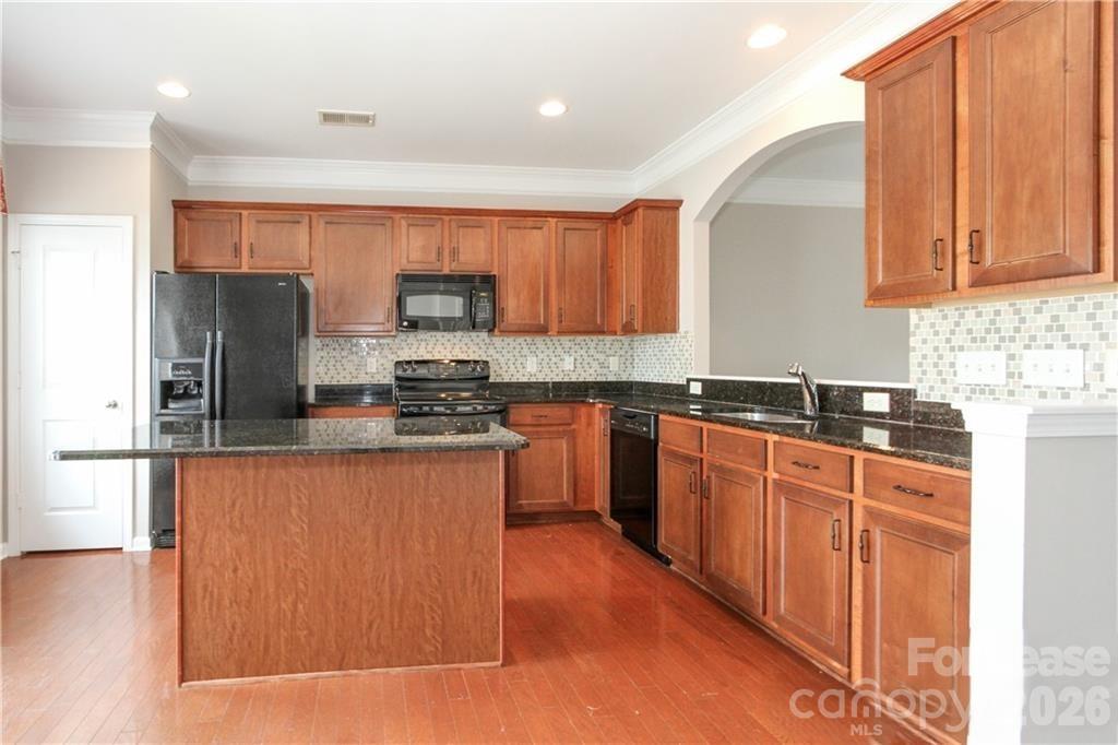 2716 Dunrobin Place Fort Mill, SC 29707 - Photo 3 of 26 a kitchen with stainless steel appliances granite countertop a refrigerator a sink dishwasher a stove top oven and a dining table with wooden floor