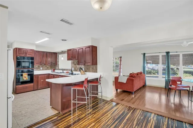 a kitchen with stainless steel appliances granite countertop a stove top oven a dining table and chairs with the wooden floor