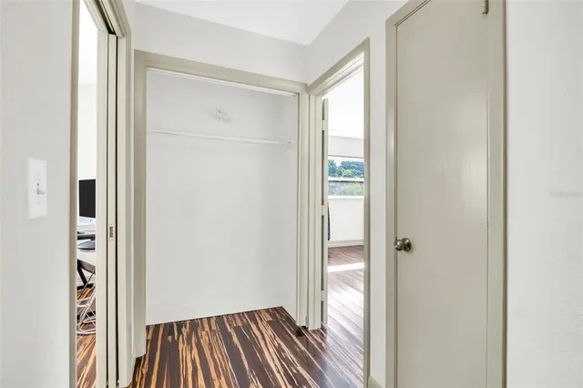 a view of a room with wooden floor closet and front door