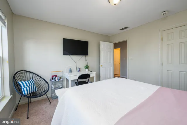 a bedroom with a bed a chair and a flat screen tv