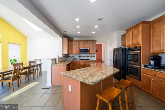 a kitchen with stainless steel appliances granite countertop table chairs sink refrigerator and granite counter top