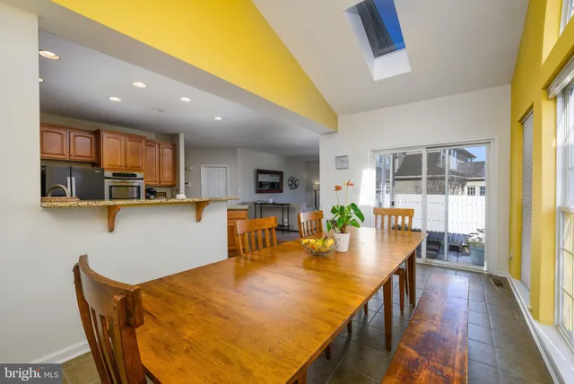 a dining room with stainless steel appliances furniture a window and kitchen view