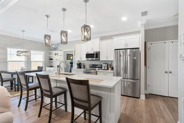 a kitchen with stainless steel appliances a dining table chairs refrigerator and microwave