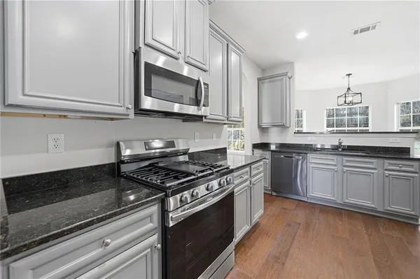 a kitchen with granite countertop a sink cabinets and wooden floor