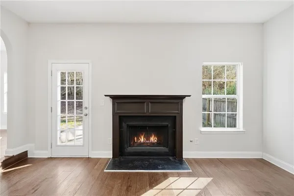 a view of an empty room with wooden floor fireplace and a window