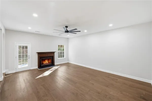 an empty room with wooden floor fireplace and windows