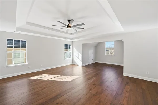 a view of empty room with wooden floor and fan