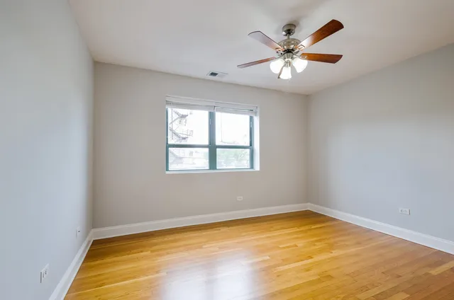 an empty room with ceiling fan and window