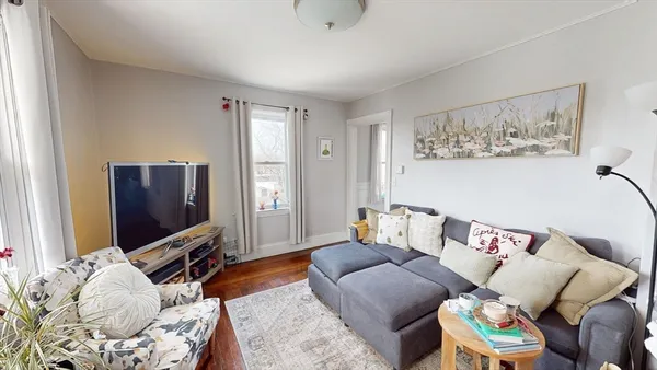 a living room with furniture a flat screen tv and a window