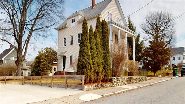 a view of a white house with a large tree