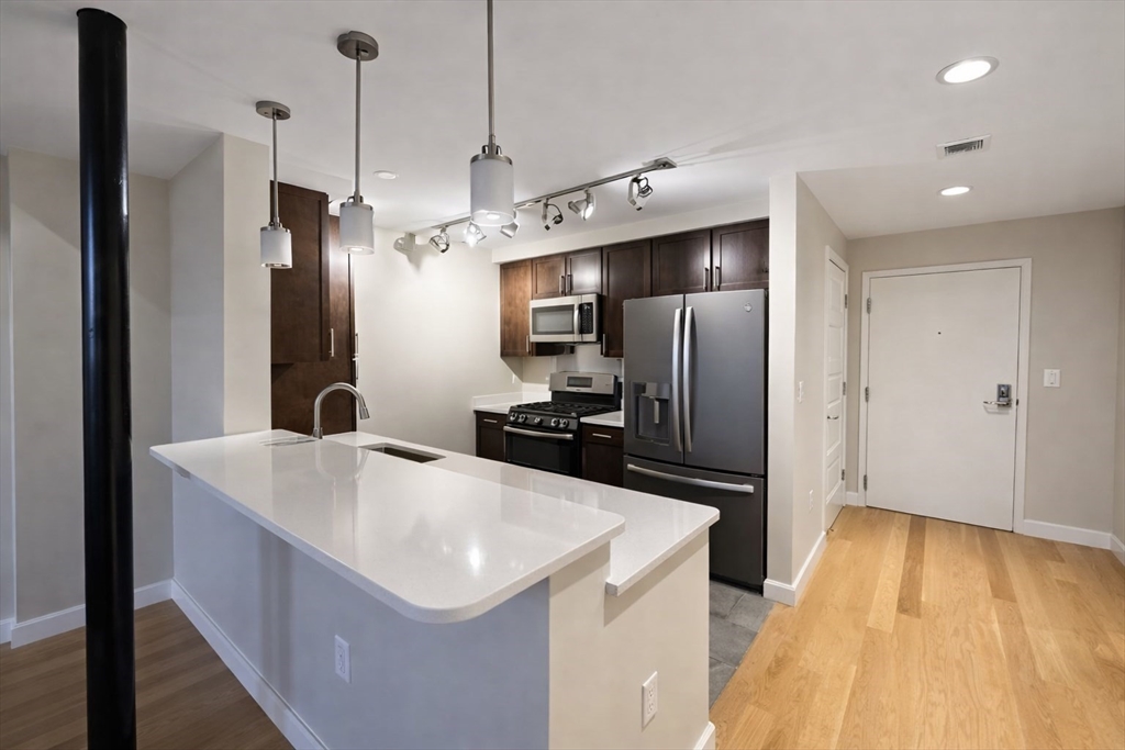 130 John Street, Unit 142 Lowell, MA 01852 - Photo 3 of 15 a kitchen with stainless steel appliances a refrigerator a sink a stove a microwave and island