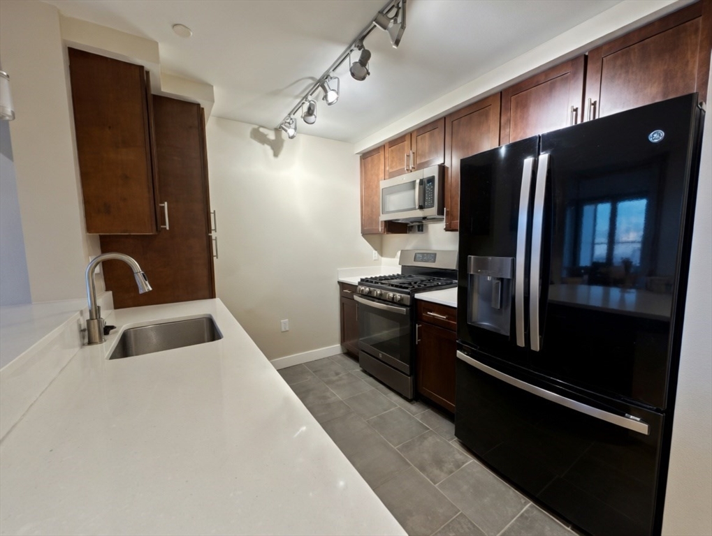 130 John Street, Unit 142 Lowell, MA 01852 - Photo 5 of 15 a kitchen with granite countertop a refrigerator and a sink