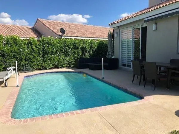 a view of a backyard with table and chairs potted plants and floor to ceiling window
