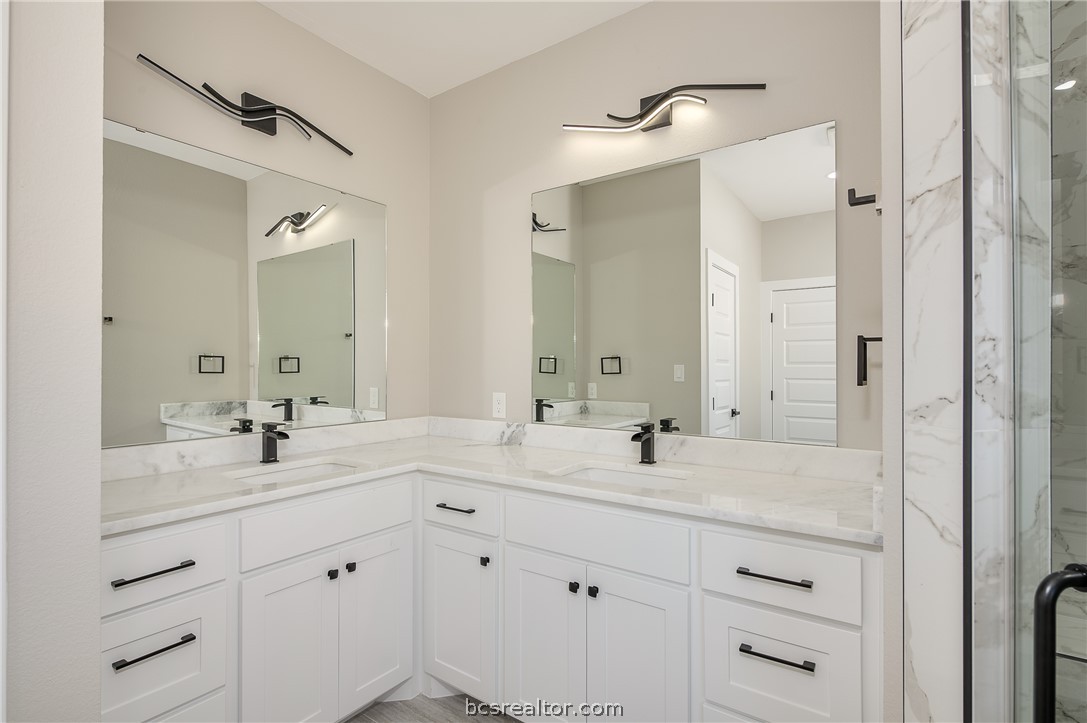 2908 GOLDBERG Drive Bryan, TX 77808 - Photo 35 of 44 Master Vanities features painted custom cabinets with hardware, quartz countertops, dark plumbing fixtures and decorative lights plus plate mirrors.