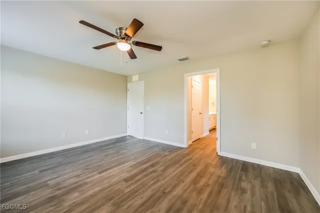 an empty room with wooden floor and a ceiling fan