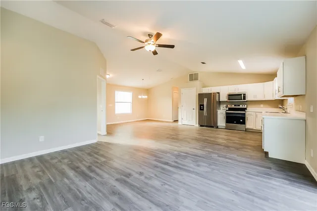 a view of kitchen with cabinets stainless steel appliances and wooden floor