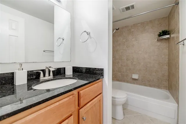 a bathroom with a granite countertop sink a toilet and shower