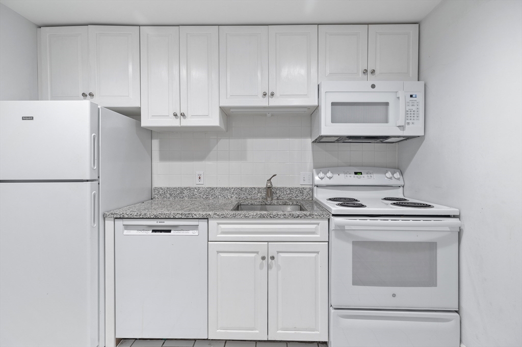 1763 Beacon Street, Unit A Brookline, MA 02445 - Photo 9 of 20 a kitchen with granite countertop white cabinets and white appliances
