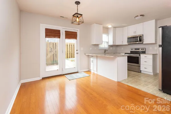 a view of a kitchen with stainless steel appliances granite countertop a stove top oven a sink dishwasher and a refrigerator with wooden floor