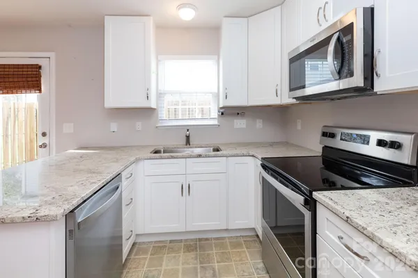 a kitchen with granite countertop cabinets stainless steel appliances a sink and a counter space