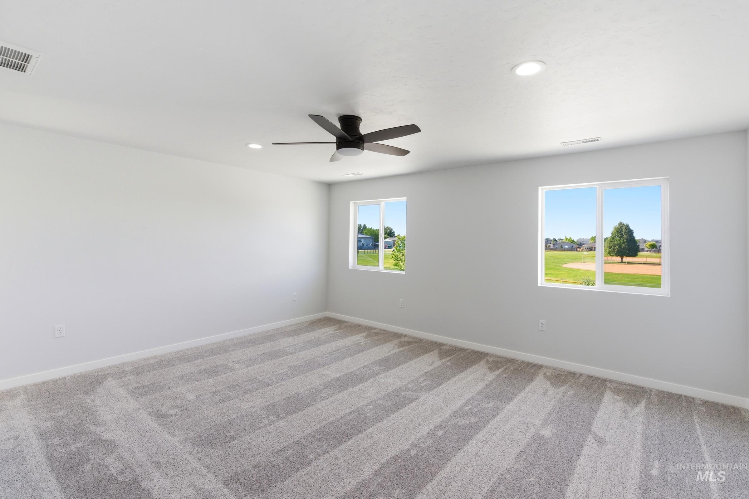 13677 Redway Court Caldwell, ID 83607 - Photo 31 of 35 Spacious room featuring light gray walls, plush carpet flooring, two double-hung windows, a ceiling fan, and recessed lighting