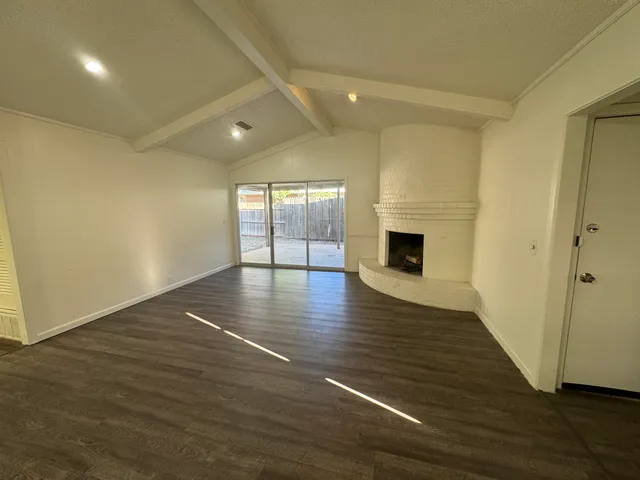an empty room with wooden floor and fireplace