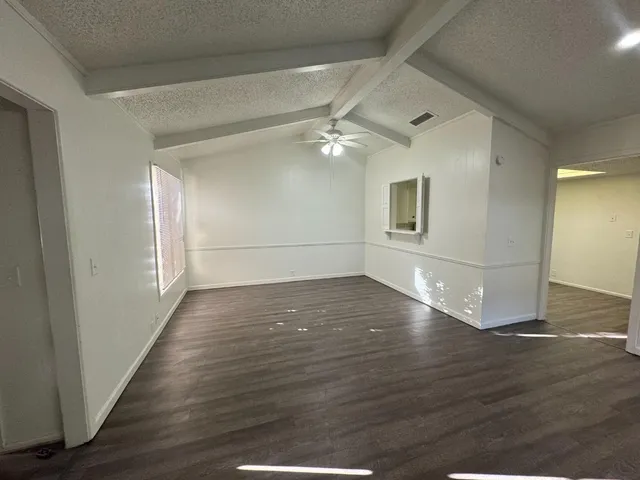 an empty room with wooden floor fan and windows