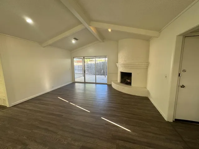 an empty room with wooden floor and fireplace