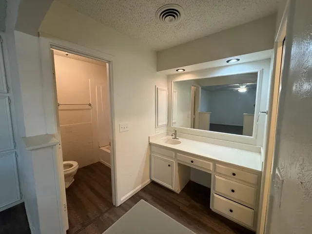 a bathroom with a double vanity sink and mirror with toilet