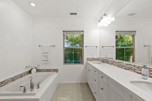 a bathroom with a tub a sink and mirror