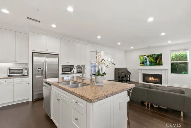 a kitchen with a refrigerator a sink dishwasher a oven with white cabinets and wooden floor