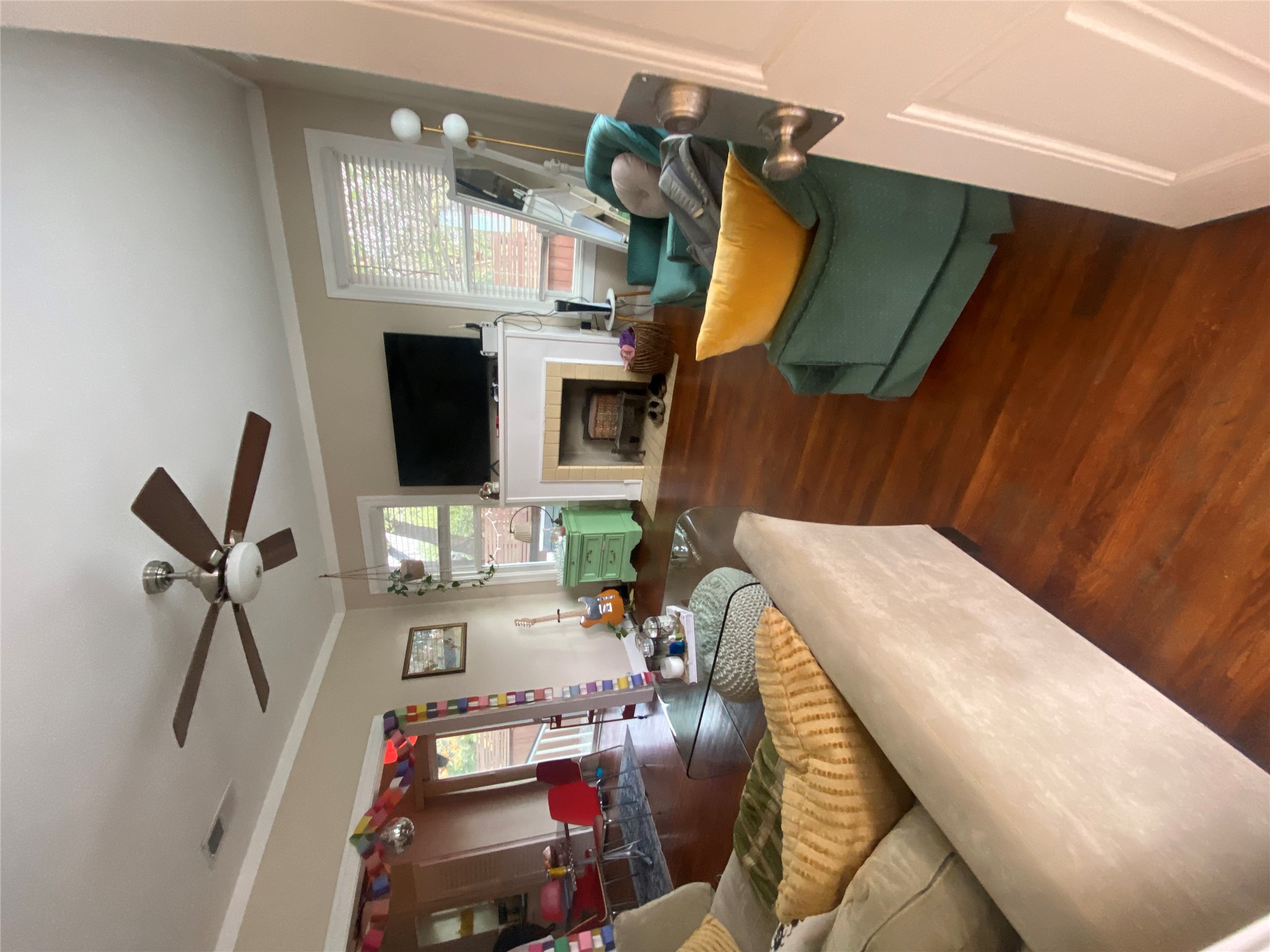3010 Fruth Street, Unit A Austin, TX 78705 - Photo 4 of 39 Living area featuring rich wood-finish flooring, a white mantelpiece, crown molding, a ceiling fan with integrated lighting, and multiple windows with blinds