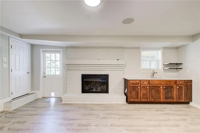 a large kitchen with granite countertop a stove a sink dishwasher and a fireplace with wooden floor