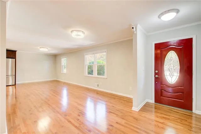 a view of an empty room with wooden floor and a window