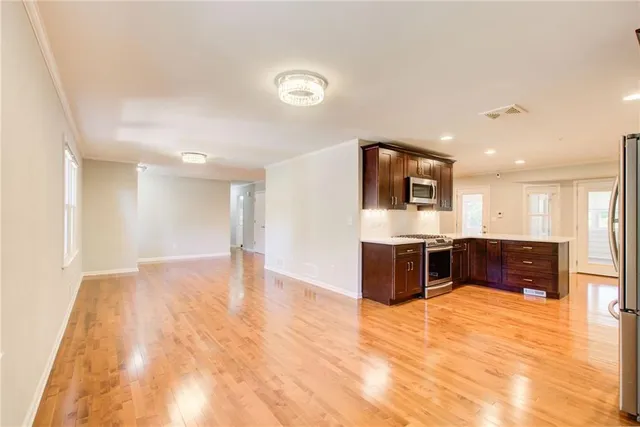 a view of kitchen with stainless steel appliances kitchen island wooden cabinets and couch